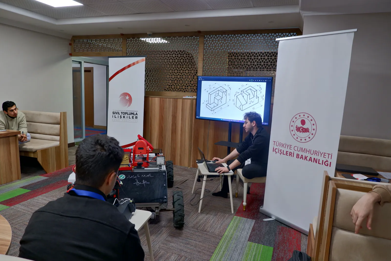 Ekranda bir CAD çizimi, önde tekerlekli bir robot