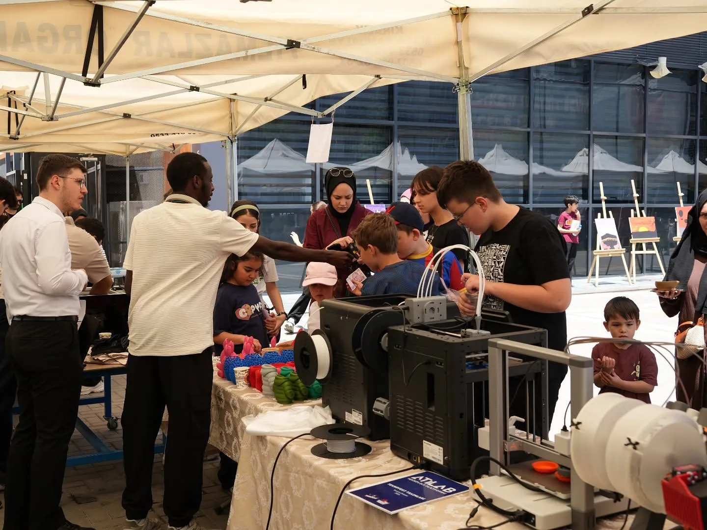Stand masasında 3D yazıcılar, çevresinde ziyaretçiler