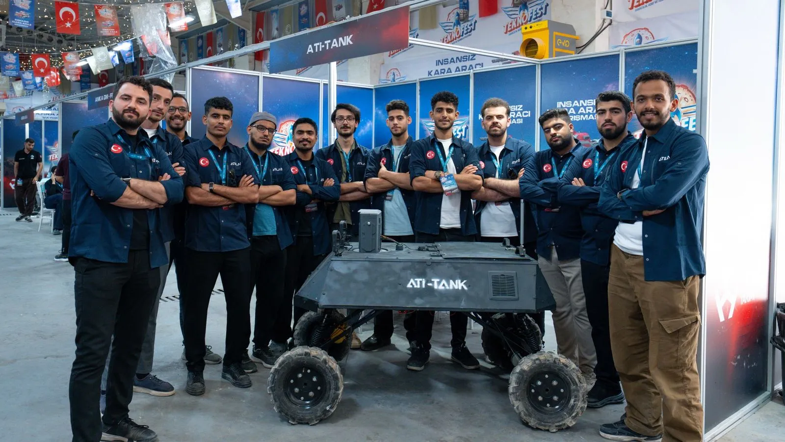 İKA takımı lacivert gömleklerle ATİ-TANK standında, araç önde