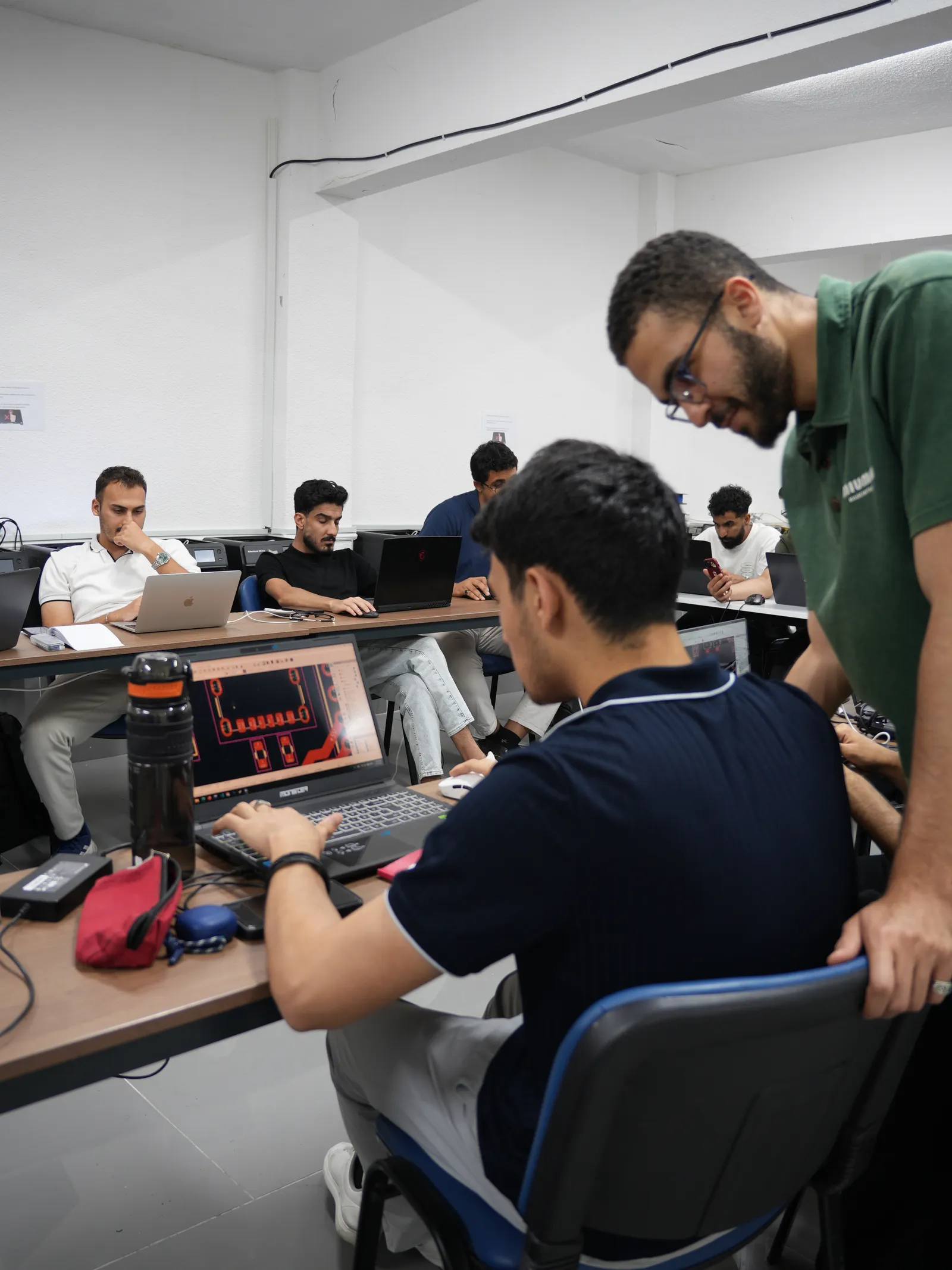 Eğitmen bir stajyerin bilgisayarındaki PCB tasarımına bakıyor